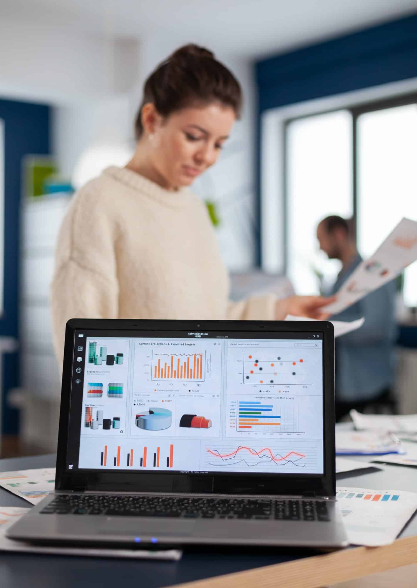 Image of an open laptop on a desk with a woman in the background on Softlinx' website