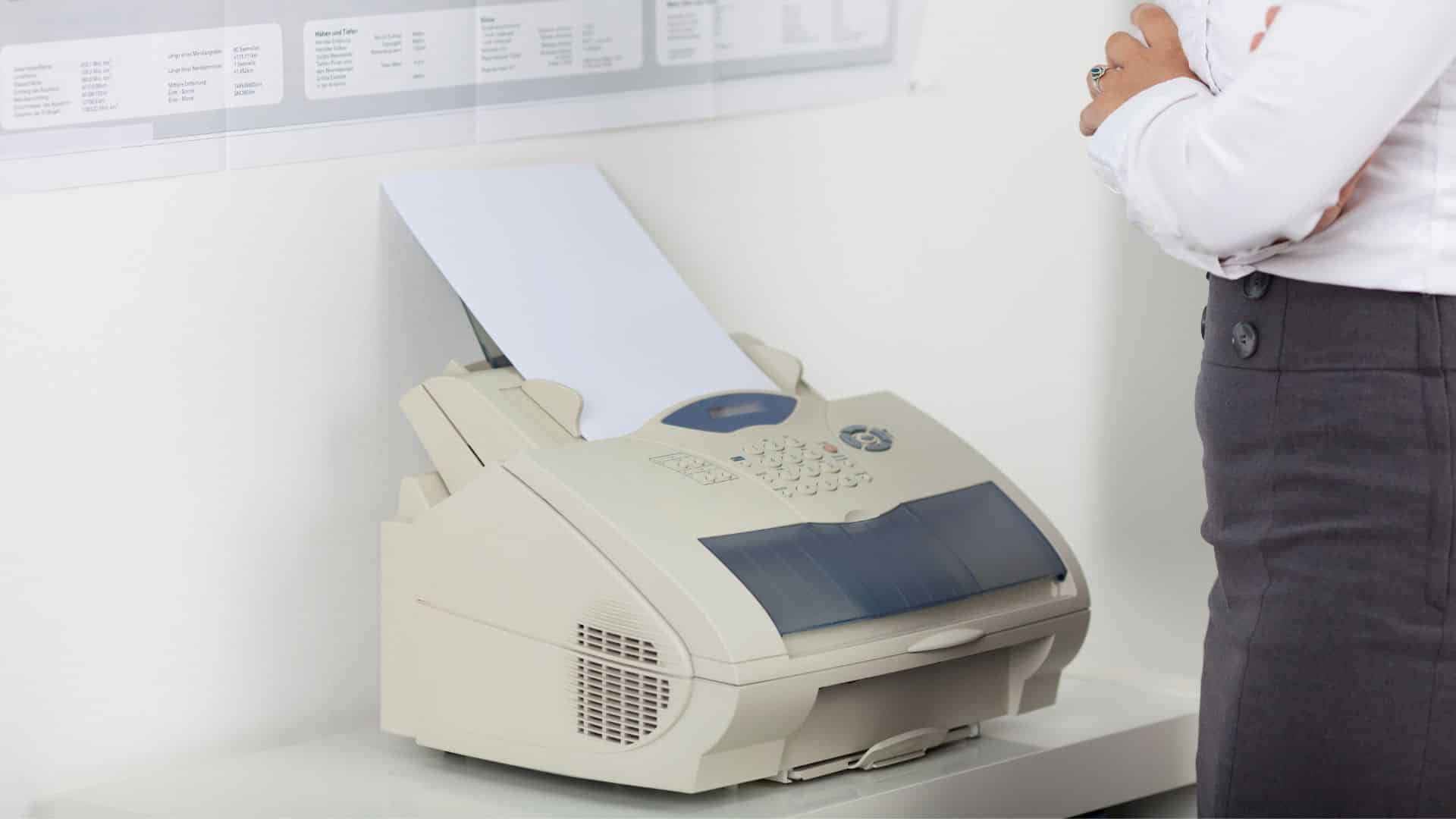 Woman standing with arms crossed next to a fax machine printing a document, with a chart of fax usage statistics in the background.