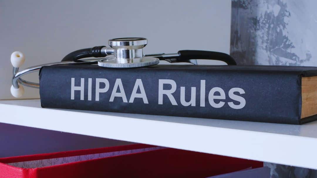 Stethoscope resting on a book titled "HIPAA Rules" – symbolizing healthcare compliance regulations.